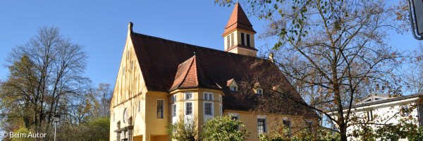 Blick von der Straße aus auf die gelbe Kirche 