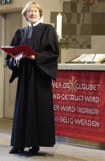Pfarrerin Ritter im schwarzen Talar vor dem Altar